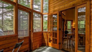 A cabin with large windows, a dining area, and a seating area with chairs.