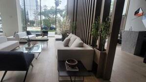 Ein modernes Wohnzimmer mit einem Glastisch, zwei Sofas und einem schwarzen Sessel.