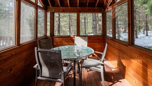 A wooden cabin with a glass table and chairs, large windows, and a view of a snowy forest. - Soda Mountain Cabin w/ Jacuzzi and Wood Stove at Green Springs Inn (Ashland)