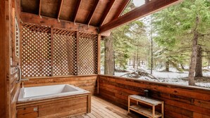 A wooden cabin with a wooden bathtub, a wooden bench, and a view of a snowy forest. - Soda Mountain Cabin w/ Jacuzzi and Wood Stove at Green Springs Inn (Ashland)