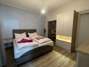 A bedroom with a bed, a wardrobe, and a desk.