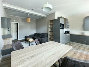 A modern apartment with a dining area, a sofa, a kitchen, and a living room.