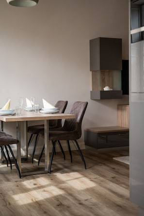 A dining area with a wooden table, dark chairs, and a modern pendant light.