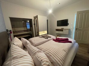 Una habitación de hotel con cama, televisor, escritorio y armario.