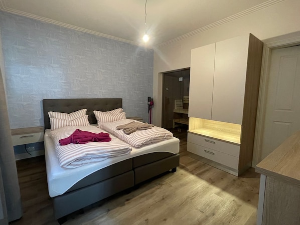 A bedroom with a bed, a wardrobe, and a desk.