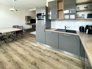 A modern kitchen with grey cabinets, a wooden countertop, and a built-in microwave.