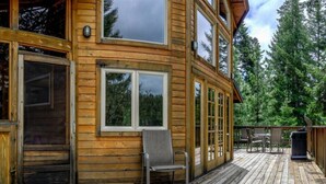 Eine Holzhütte mit Terrasse, großen Fenstern und einem Stuhl.