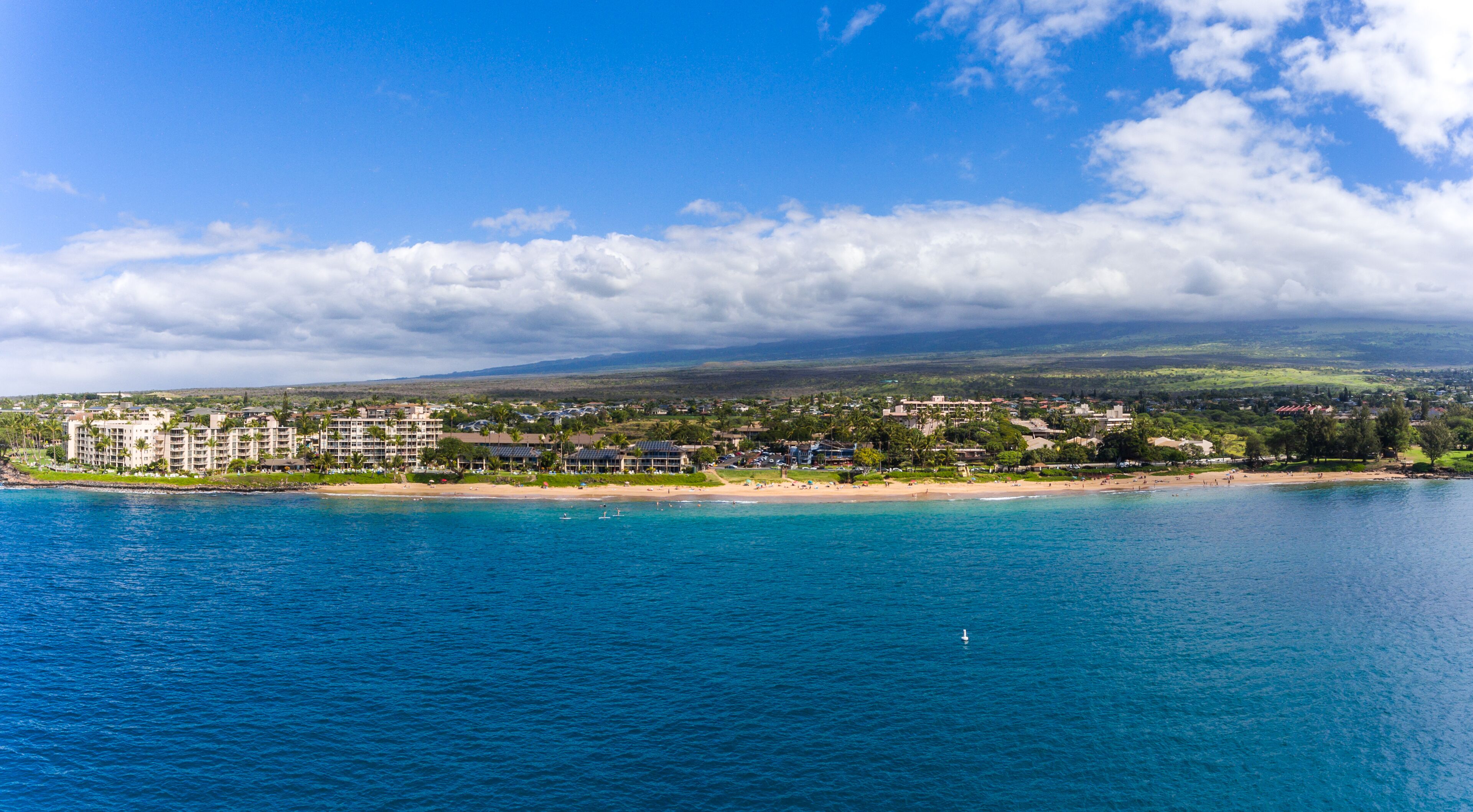 A coastal resort with beachfront accommodations, a sandy beach, and a view of the ocean and distant hills.