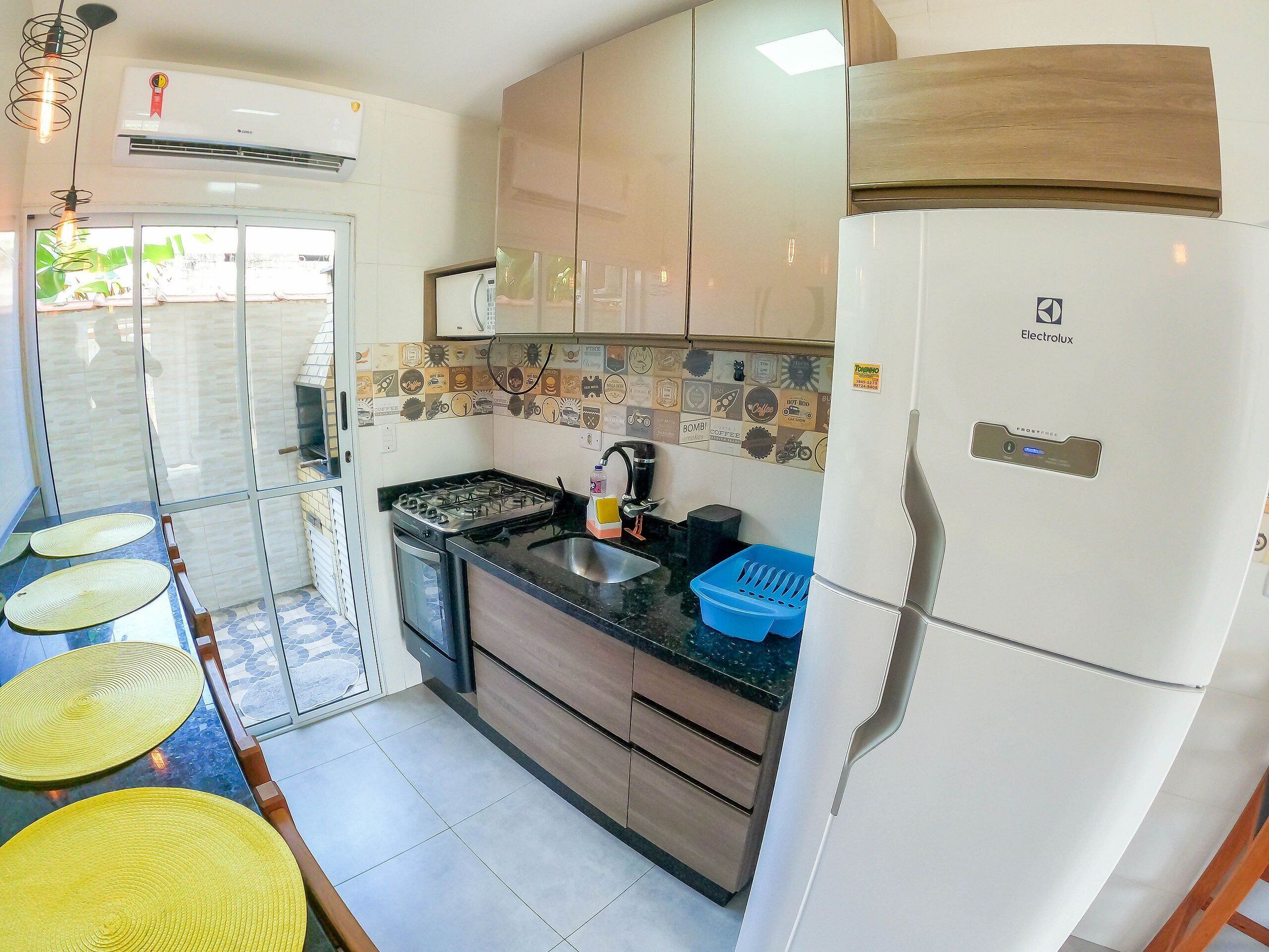Una cocina compacta con estufa a gas, pileta y un refrigerador blanco.