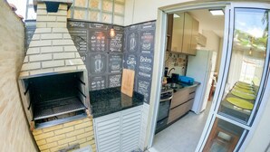 A compact kitchen with a built-in oven, a small countertop, and a sliding door leading to a dining area. - Severos mar 2 (Ubatuba)