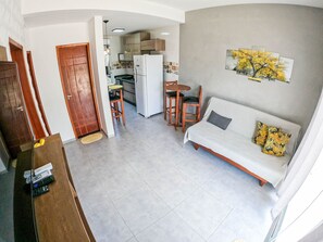 A compact living space with a kitchenette, a dining area, and a sofa with decorative pillows. - Severos mar 2 (Ubatuba)
