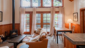A cozy cabin interior with a wooden interior, a fireplace, a dining table, and a sofa. - Boccard Point Cabin w/ Jacuzzi and Wood Stove at Green Springs Inn (Ashland)