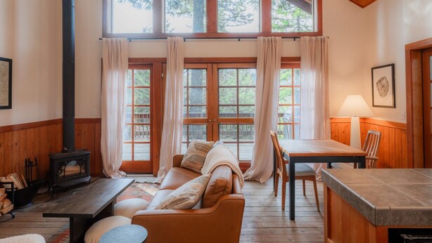 A cozy cabin interior with a wooden interior, a fireplace, a dining table, and a sofa. - Boccard Point Cabin w/ Jacuzzi and Wood Stove at Green Springs Inn (Ashland)