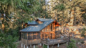 A cabin with a wooden exterior, a metal roof, and a stone foundation. It is surrounded by trees and has a wooden deck. - Boccard Point Cabin w/ Jacuzzi and Wood Stove at Green Springs Inn (Ashland)