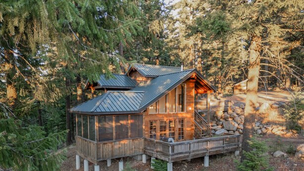 A cabin with a wooden exterior, a metal roof, and a stone foundation. It is surrounded by trees and has a wooden deck. - Boccard Point Cabin w/ Jacuzzi and Wood Stove at Green Springs Inn (Ashland)