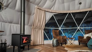 A cozy room with a wood-burning stove, leather chairs, and a large window with a geometric view. - Scribbly Farm Premium Dome Bush retreat Southern highlands (High Range)
