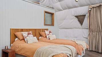 A bedroom with a wooden headboard, two beds, a window, and a curtain.