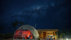 A geodesic dome structure with a wooden deck and a covered seating area under a starry night sky. - Scribbly Farm Premium Dome Bush retreat Southern highlands (High Range)