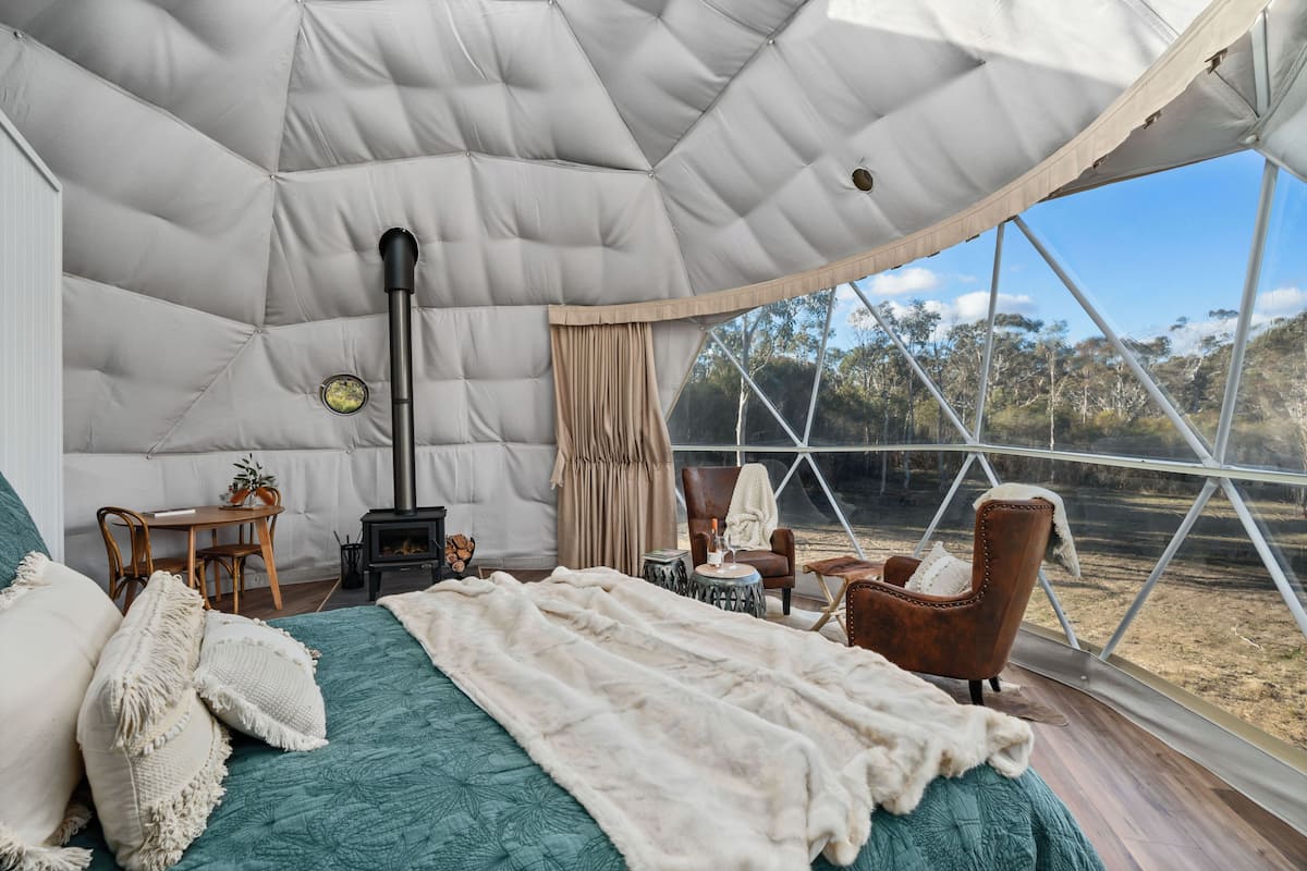 A spacious tent with a bed, a table, and a chair.