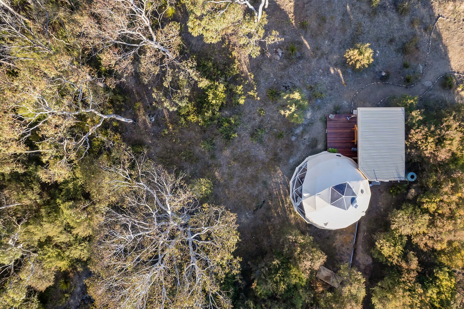 Vista aérea de una propiedad con un edificio circular, una construcción rectangular y un cobertizo pequeño.