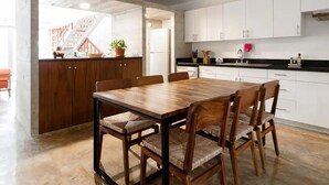 Una cucina moderna con mobili bianchi, un tavolo da pranzo in legno e una scala che conduce a un piano superiore.