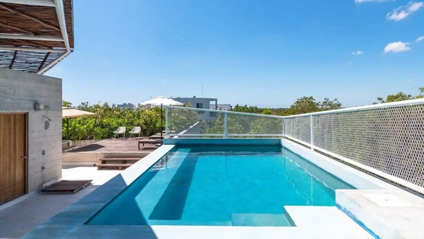 Una piscina sul tetto con un cielo azzurro limpido sullo sfondo.
