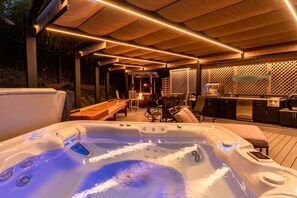 Relax in a hot tub area with a modern hot tub, comfortable seating, and a grill.