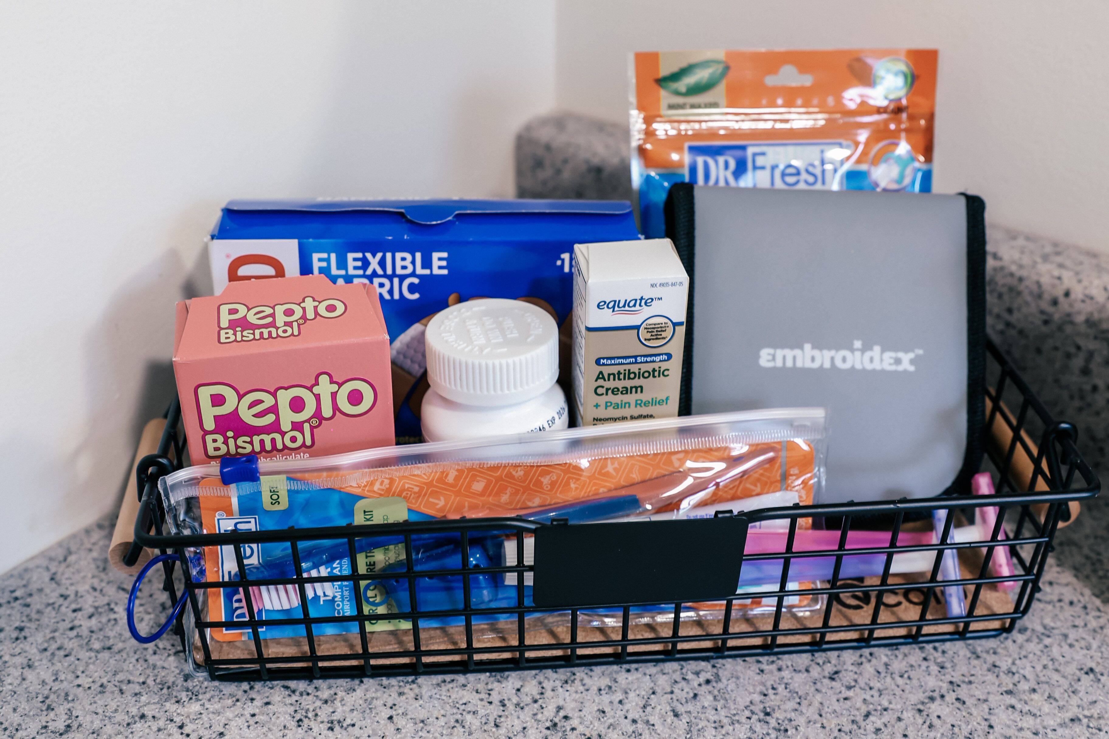 En korg som innehåller Pepto Bismol, Flexi Wrap, Equate antibiotisk kräm, Embroidex och andra produkter.