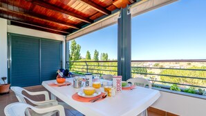 A balcony with a table set for breakfast, including a coffee maker, a fruit bowl, and a bottle of juice. - Great and Spacious apartment overlooking the Swimming-Pool (Lagos)