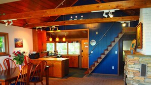 A spacious kitchen with wooden cabinets, a dining area with a blue couch, and a stone fireplace.