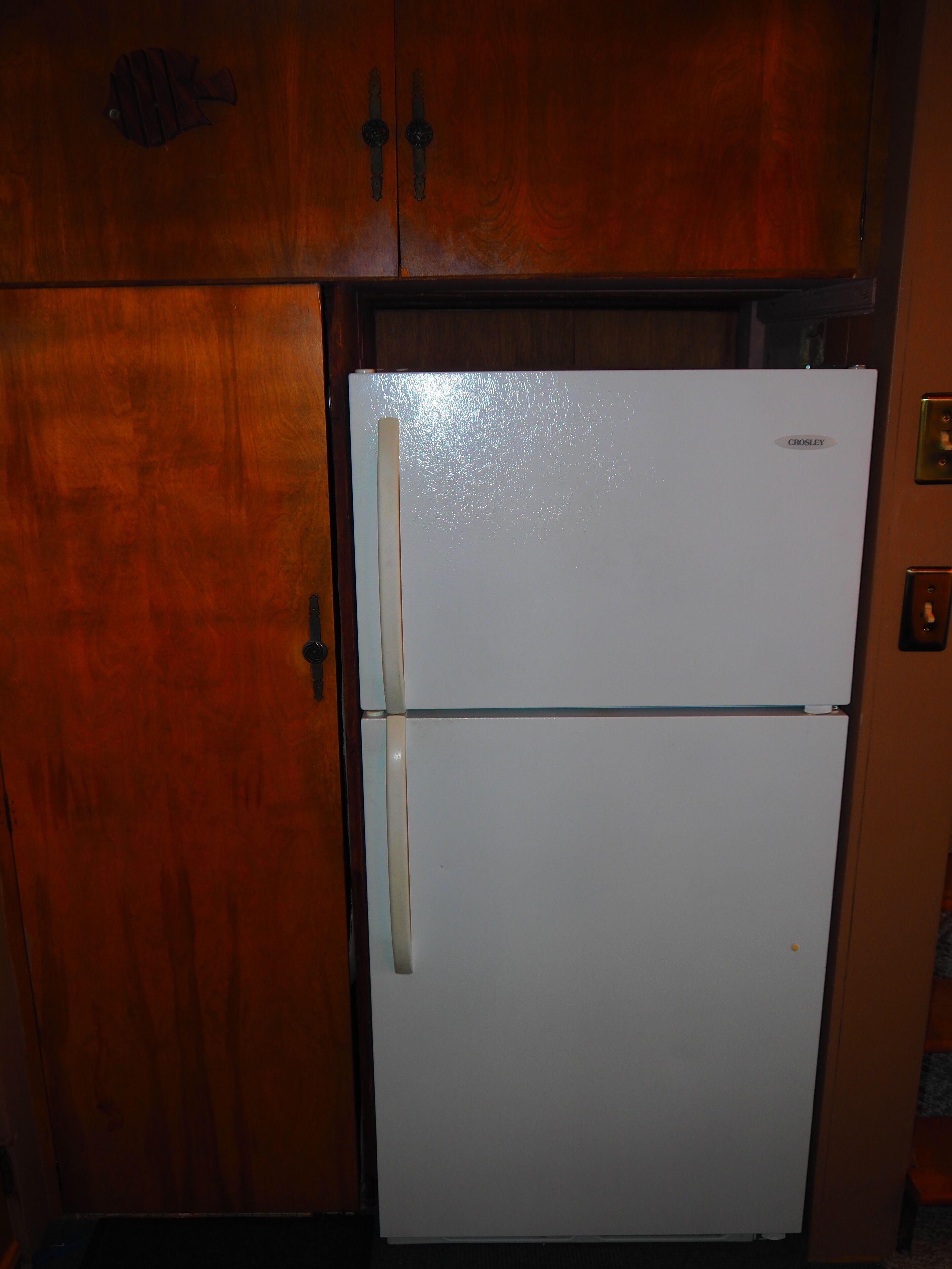 Ein weißer Crosley-Kühlschrank in einer Küche mit Holzschränken.