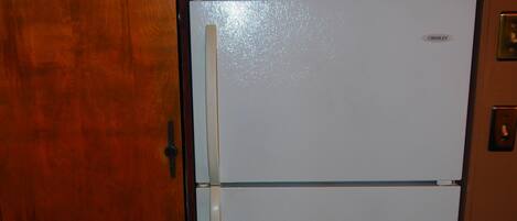 Ein weißer Crosley-Kühlschrank in einer Küche mit Holzschränken.