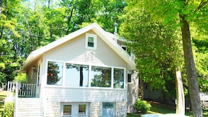 A house with a stone foundation, large windows, and a covered porch.
