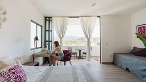 A bedroom with a bed, a desk, and a view of the outdoors. - Casa Fénix - Sayulita (Sayulita)