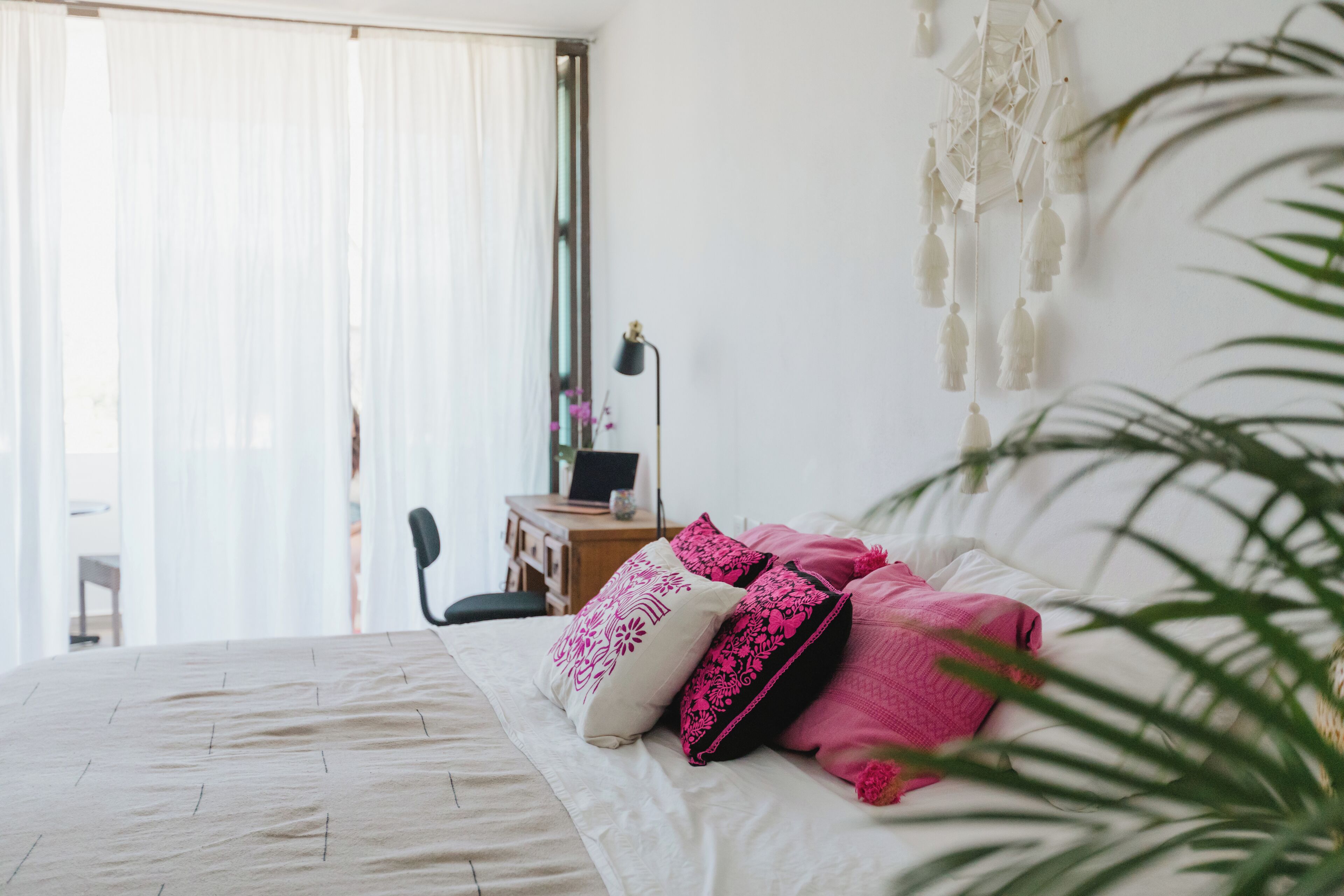 A bedroom with a bed, pillows, a desk, and a chair.