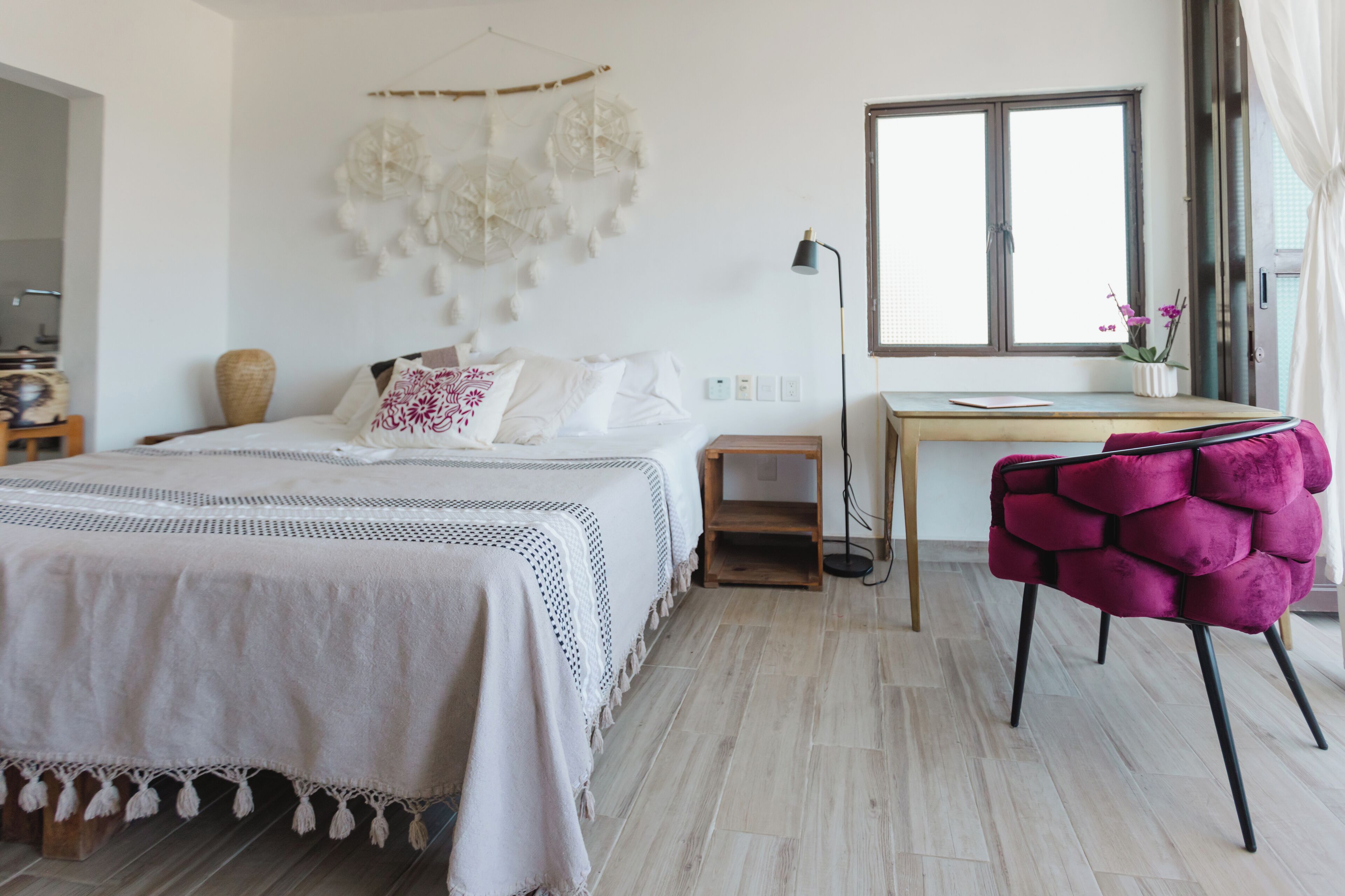 A bedroom with a bed, bedside table, lamp, window, and a chair.
