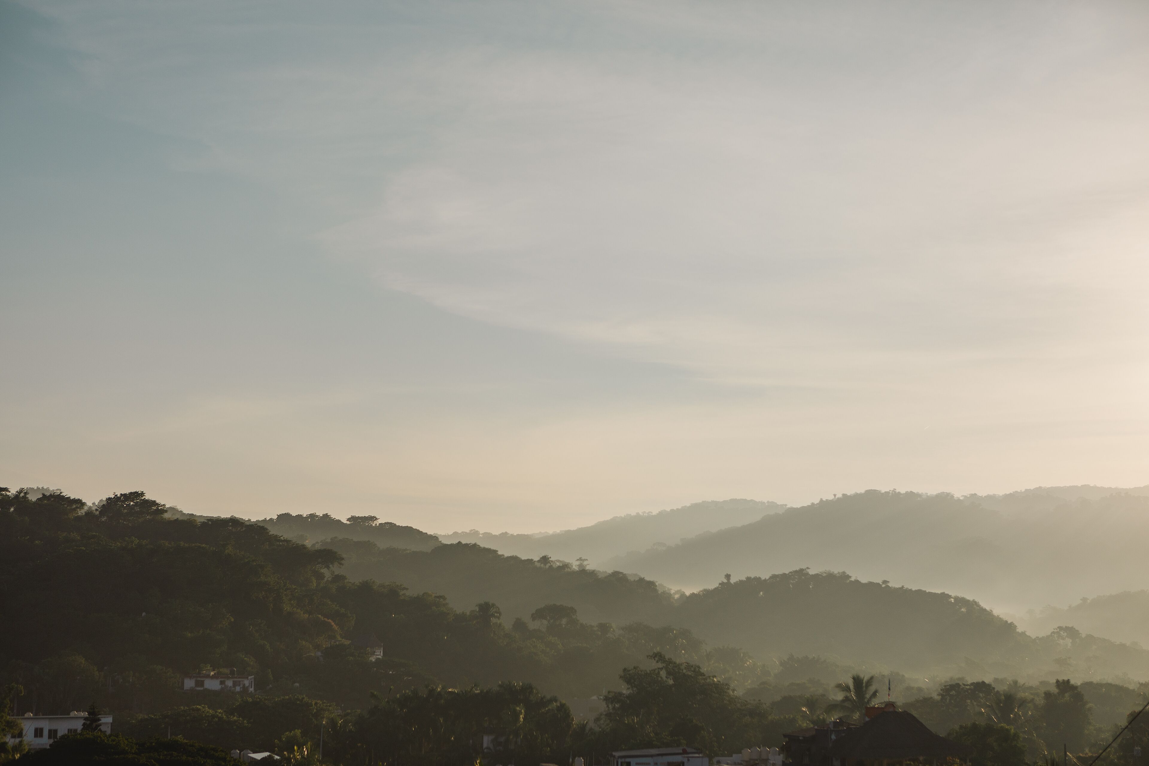 A hilly landscape with a few buildings and trees.