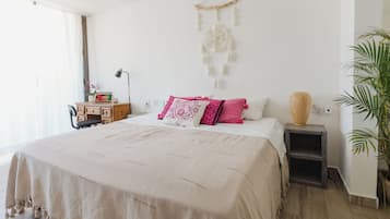 Une chambre à coucher comprenant un lit, des tables de chevet, un bureau, une chaise et un attrape-rêves suspendu.