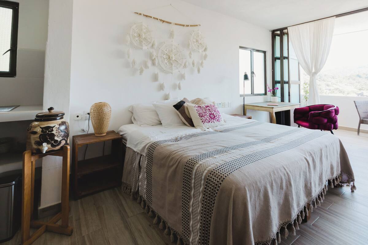 Un dormitorio con cama, mesitas de noche, escritorio y silla.