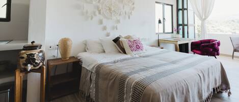 A bedroom with a bed, bedside tables, a desk, and a chair.
