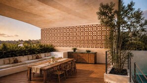 An outdoor patio with a wooden table and chairs, a decorative wall, and a potted plant. - Casa Fénix - Sayulita (Sayulita)