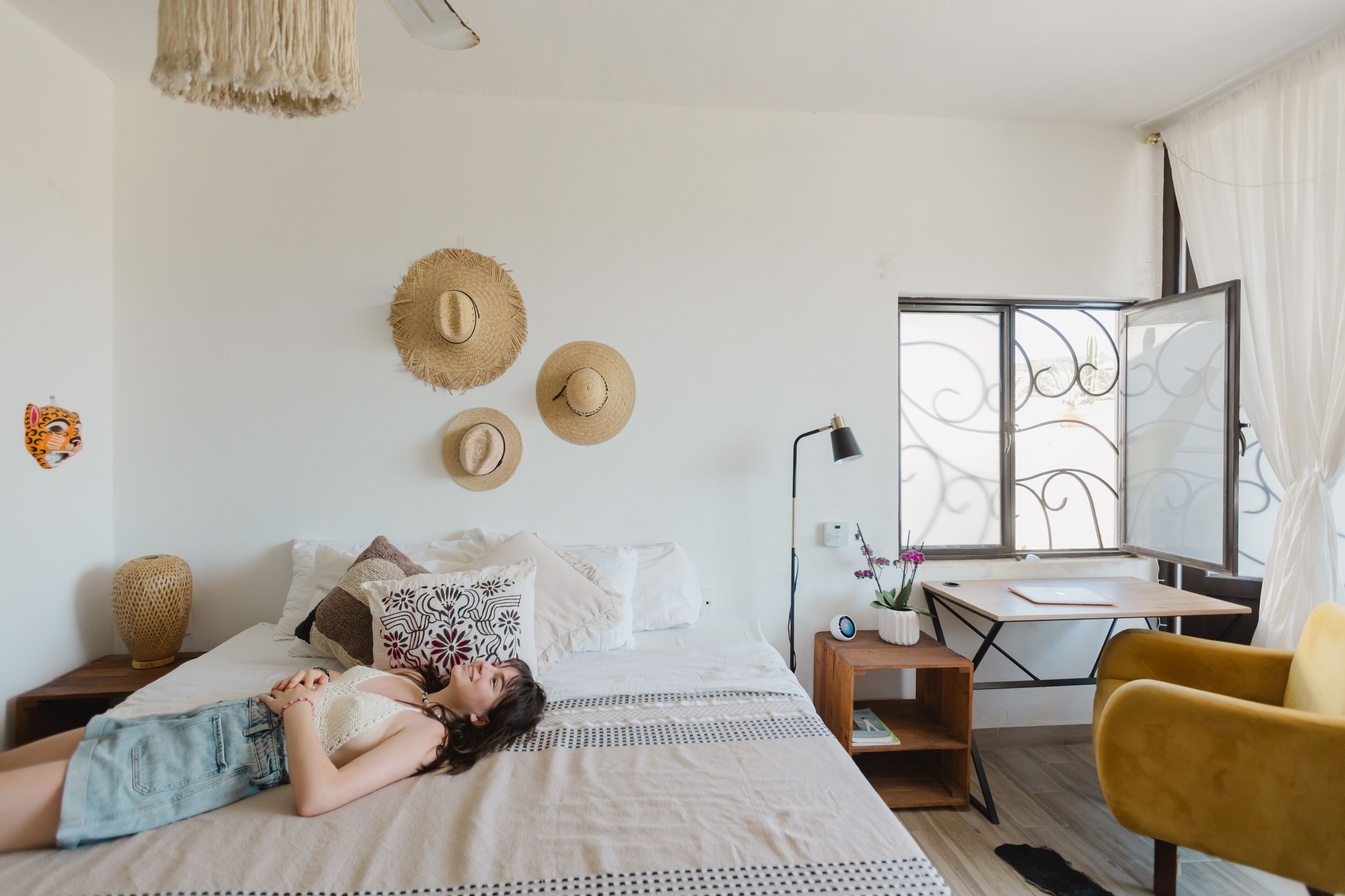 A bedroom with a bed, a desk, a chair, and a window with a view.
