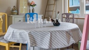 Uma mesa de jantar com toalha listrada, um vaso com flores e uma garrafa.