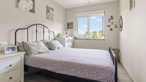 A bedroom with a bed, bedside table, lamp, and window.