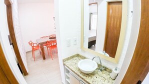 A bathroom with a sink, mirror, and a small table with chairs. - Geneis  (Ubatuba)