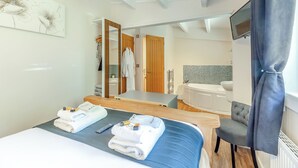 A hotel room with a bed, a desk, a chair, a TV, a bathroom with a bathtub, and a shower. - 2 bedroom accommodation in Ellesmere (Ellesmere)