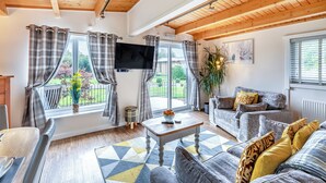 A living room with a sofa, a coffee table, and a TV mounted on the wall. - 2 bedroom accommodation in Ellesmere (Ellesmere)