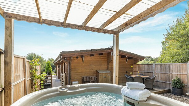 A hot tub under a wooden pergola with a wooden cabin in the background. - 2 bedroom accommodation in Ellesmere (Ellesmere)