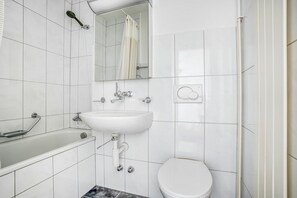 A modern bathroom with a white sink, a toilet, and a shower area.