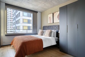 A bedroom with a bed, a window, a wardrobe, and artwork on the wall. - Inviting Oerlikon 2BR w/ Storage Space & W/D, nr Market, by Blueground (Zurich)
